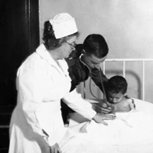 ELLIS ISLAND: EXAMINATION. A doctor and nurse examining a baby in a hospital at Ellis Island