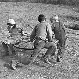 Farm children playing on a homemade merry-go-round. Photograph, 1937, by Russell Lee