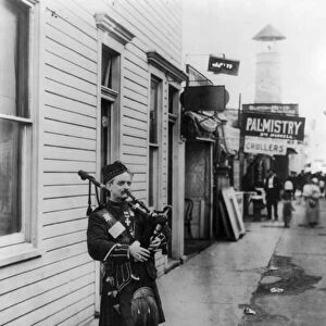 SCOTTISH BAGPIPER, c1912. Bagpiper playing on a street corner at Coney Island, Brooklyn, New York