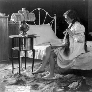 WOMAN READING, c1897. A young woman finishing a book before going to bed. Photograph