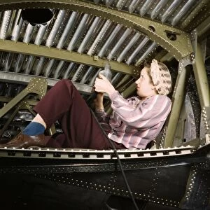 A woman riveter working on an A-20 Havoc light attack bomber at the Douglas Aircraft Company plant in Long Beach, California, October 1942. Photographed by Alfred T. Palmer