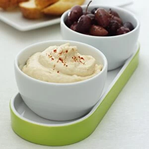 Bowl of Taramasalata, dip made from cods roe, served with bowl of black olives and sliced white bread, close-up