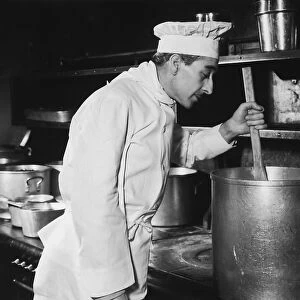 Chef stirring soup in large pot on stove