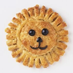 Circular shaped pastry decorated with olives to resemble a lions face, view from above