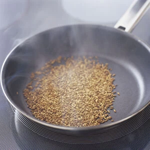 Fennel seeds dry-roasting in a frying pan