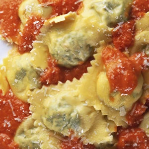 Filled pasta in tomato sauce, sprinkled with grated cheese, close-up
