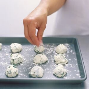 Flouring the tops of ricotta and spinach dumplings (malfatti) placed on a baking tray
