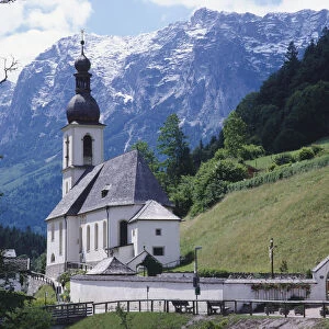 Germany, Bavaria, Berchtesgadener Land region, Ramsau an der Ache, small parish church set in the Ramsau Valley with snow-capped mountains as a backdrop