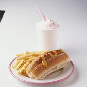 Hot dog with mustard and chips and milkshake on side