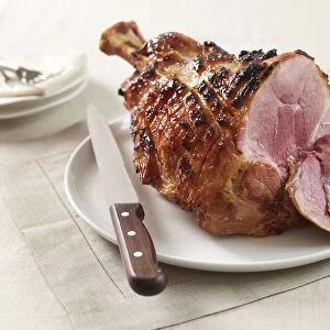 Mustard glazed ham on a plate, with a carving knife