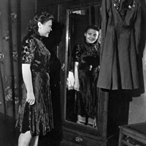 Nina lobkovskaya in war and peace, like all young girls, nina loves pretty clothes, here she is trying on a dress during a shopping trip, if it were not for her uniform with its decorations hanging nearby, no one would guess that she has been through the war, 1940s