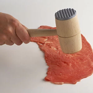 Pounding slice of red meat with meat mallet, high angle view