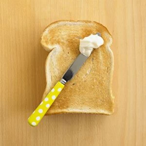 Slice of toasted white bread with knife and blob of mayonnaise on top
