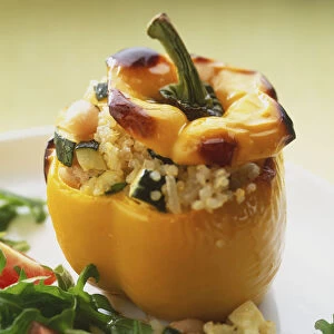 Yellow pepper, stuffed with mixture of courgettes and grains, salad garnish in front