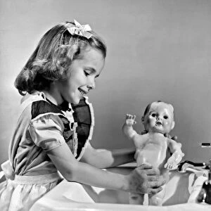 A young girl plays with her new all-vinyl plastic doll that can be washed without fear of damage