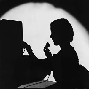 ARCHIVE SHOT / SILHOUETTE OF SWITCHBOARD OPERATOR / INDOORS