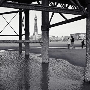 Father with children (10-13) on beach, view through pier supports