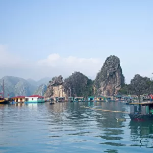 Floating Vietnamese fishing village with rocky coastline
