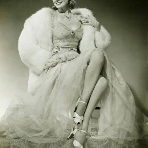 Glamorous woman in evening dress showing legs, posing in studio, (B&W), portrait