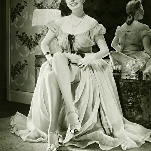Glamorous woman in evening gown showing legs, (B&W), portrait