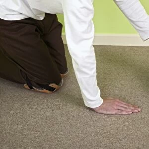 Man installing carpet tiles on top of plywood floor