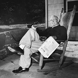 Mature man in rocking chair with pipe and newspaper (B&W)