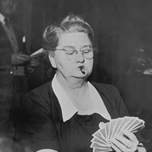 Mature woman playing cards, smoking cigar (B&W)