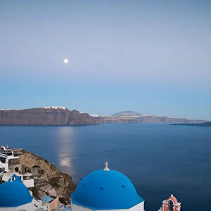 Moon over village of Oia with blue dome church