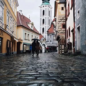 Two persons with one umbrella wandering in the cobbled streets in the old town of Cesky Krumlov, South Bohemia, Czech Republic