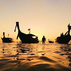 Silhouette of a longtail boat and fisherman at sunset in Krabi, Thailand