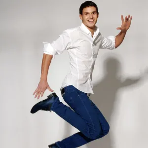 Young man in white shirt and blue jeans jumping