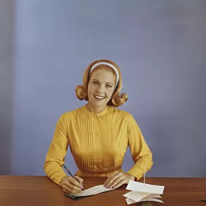 Young woman filling out bank slip, smiling, portrait