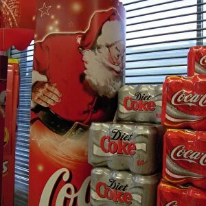 Six can packs of Coca-Cola and Diet Coke next to a giant poster of Father Christmas