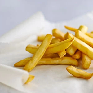 Pile of french fries on greaseproof paper credit: Marie-Louise Avery / thePictureKitchen