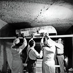 Discovery of the tomb of pharaoh Tutankhamun in the Valley of the Kings (Egypt) : here in burial chamber, Howard Carter, Arthur Callender and egyptian workers removing the lifting one roof section from the first, outermost shrine, december 1923