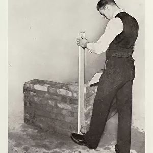 Plumbing for correct position of quoin with plumb-rule and lead-bob (b/w photo)