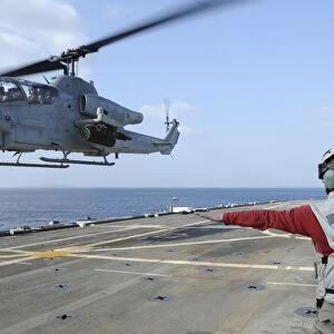 An AH-1W Cobra helicopter takes off from USS Denver
