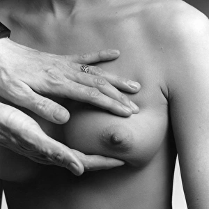 A female nude from the waist up with a doctors hands conducting a clinical breast