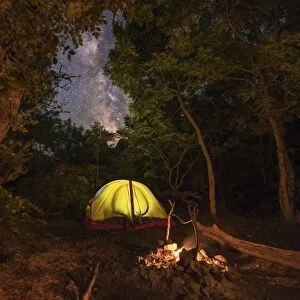 Illuminated tent and a fire under the Milky Way in Foros, Crimea