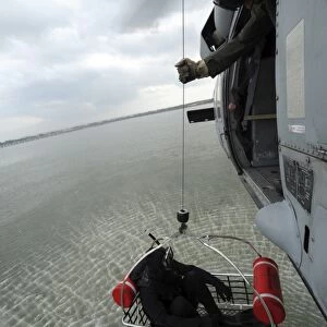 Naval Air Crewman hoists a rescue basket into an MH-60S Sea Hawk helicopter