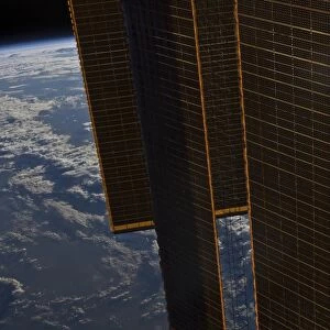 Solar panels of the International Space Station backdropped by a blue and white Earth