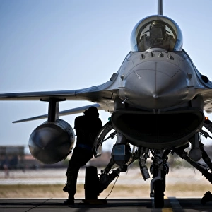 U. S. Air Force crew chiefs do pre-flight checks under an F-16 Fighting Falcon