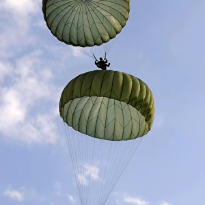 U. S. Army Soldiers parachute down after jumping from a C-130 Hercules
