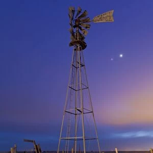 Venus and Jupiter are visible behind an old farm water pump windmill, Alberta, Canada