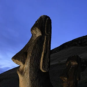 Moai stone statue at dusk on the slopes of the quarry at Rano Raraku volcano, Easter