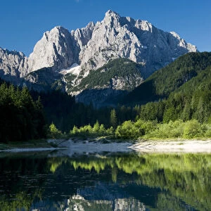 Mount Prisojnik (2, 547m) with reflection in a small pond beside the river Pisnica