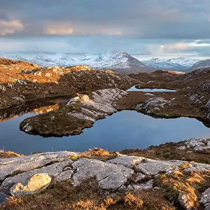 Remote hill lochan with view towards Loch Torridon and Ben Damph, in late winter light, Wester Ross, Scotland, UK, March 2017
