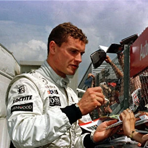 1997 BRITISH GP. David Coulthard signs autographs for the fans. Photo: LAT