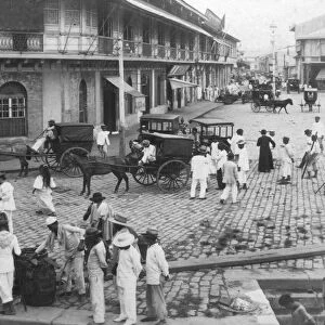 Historic image in black and white of people on the cobblestone street in Binondo, a Chinatown district in Manila, Philippines. People are outside a church with horses and wagons; Manila, Philippines