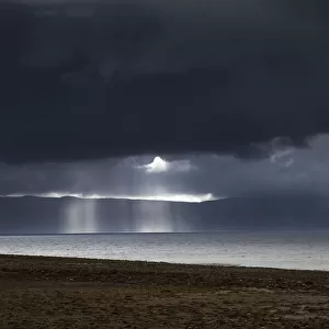 Sunbeams shine through dark storm clouds over the water; Applecross peninsula highlands scotland